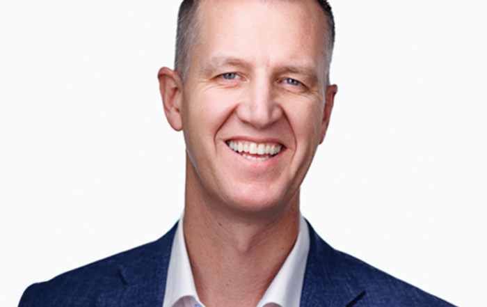 Business professional headshot of man in navy blazer against white background