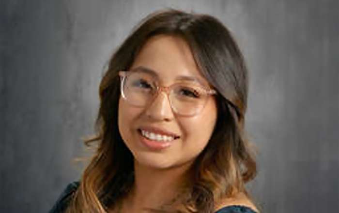 Professional headshot of woman wearing glasses and dark blue top
